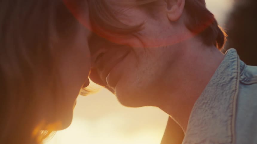 An intimate close-up of a smiling couple touching foreheads, bathed in the warm, golden light of sunset