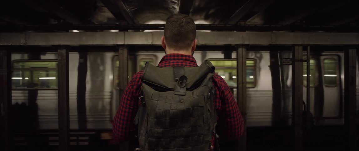 Man with a backpack standing in front of a moving subway