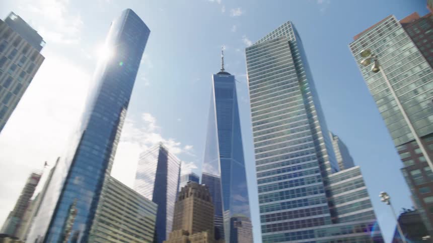 A slow-moving shot pans across the sun-drenched skyscrapers of downtown New York City from a low angle