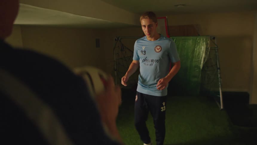 A young soccer player receives a pass from his coach and skillfully juggles the ball in slow motion during an indoor training session
