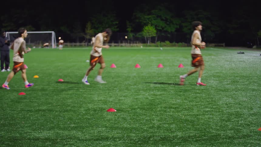 Soccer players run agility and speed drills during an intense nighttime practice on an athletic field