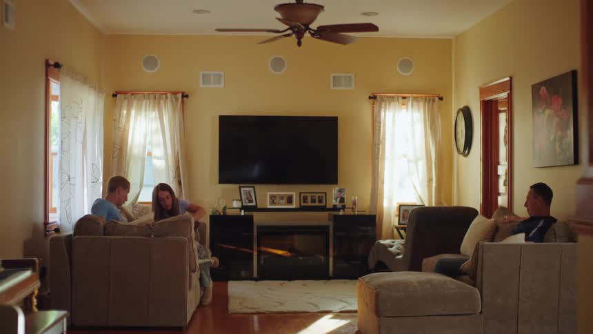 A family of four enjoys a quiet, relaxing afternoon together in their comfortable, sunlit living room
