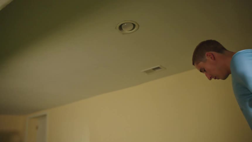 A young male soccer player practices kicking and dribbling drills in his basement training area in slow motion