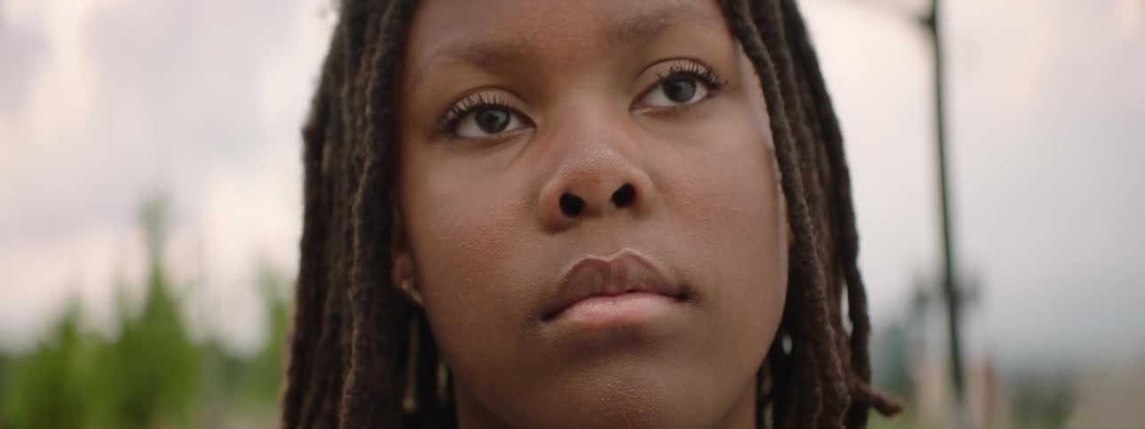 A powerful low-angle close-up of a contemplative young Black girl with dreadlocks looking upward
