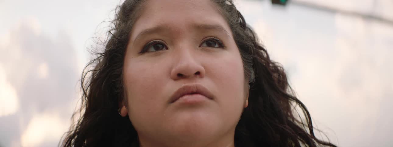 Close up of a determined young woman's face slowly coming into focus as she gazes upwards