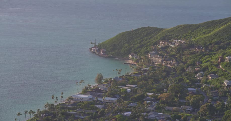 High-angle scenic view of a lush green Hawaiian coastline with a beautiful bay and coastal homes