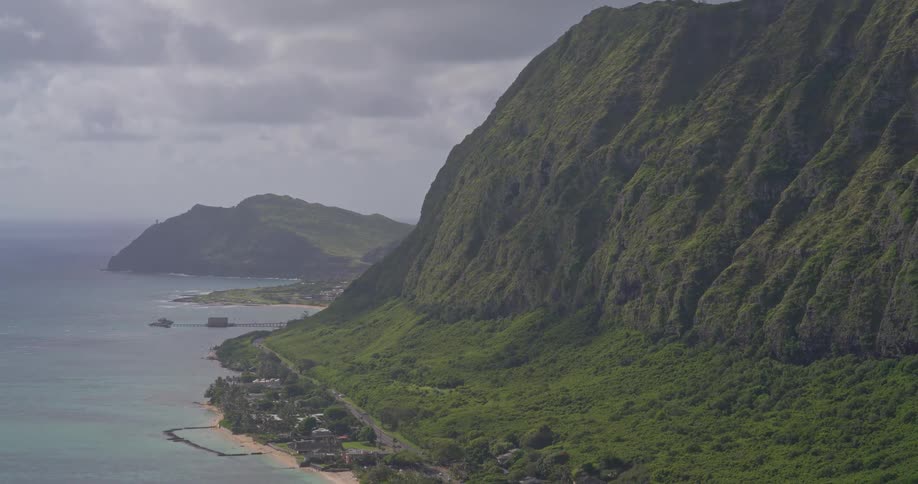 A breathtaking high-angle, static shot of the lush, green Koolau mountain range along the coast of Oahu, Hawaii, on a cloudy day