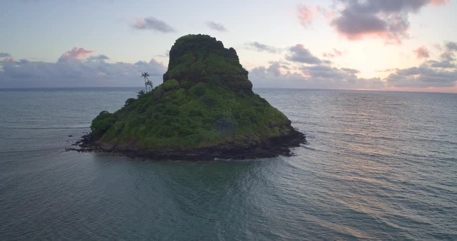 A scenic view of Mokoli'i Island, also known as Chinaman's Hat, off the coast of Oahu, Hawaii, during a peaceful sunrise