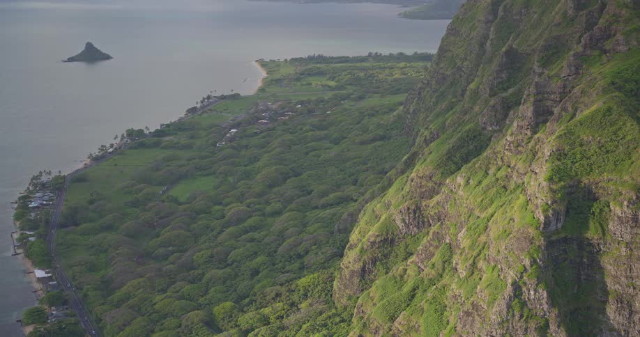 A majestic, high-angle view of the rugged green cliffs overlooking the lush coastline and ocean on the island of Oahu, Hawaii