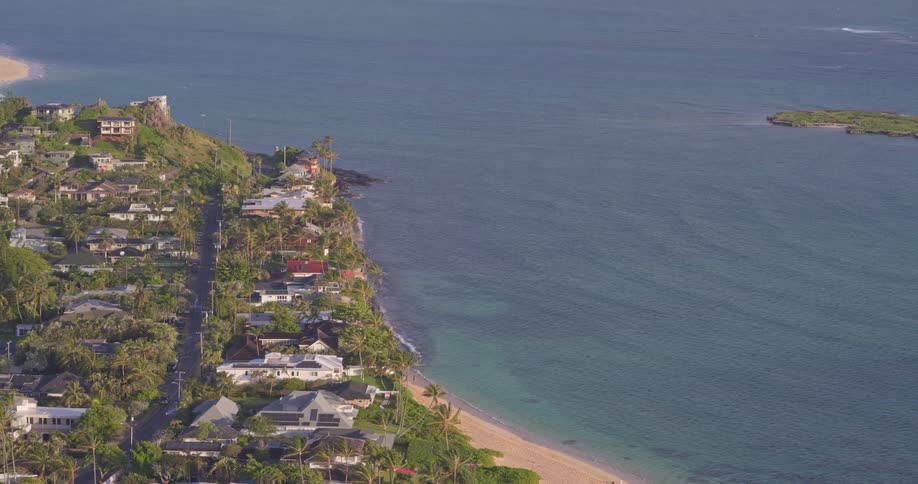 Scenic overview of a picturesque Hawaiian village nestled along a white sand beach and the Pacific Ocean