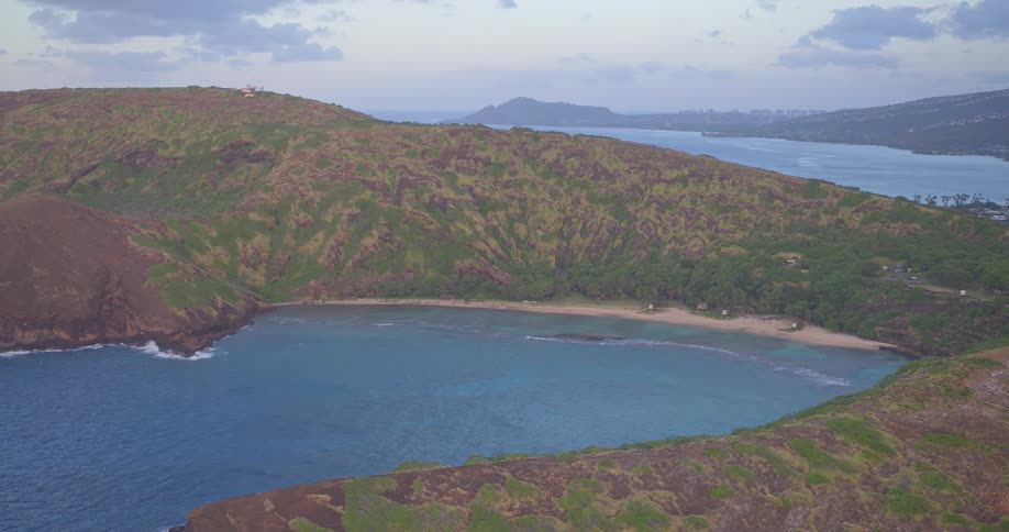 A serene, wide-angle view captures the iconic volcanic crater and turquoise waters of Hanauma Bay in Oahu, Hawaii, at dusk