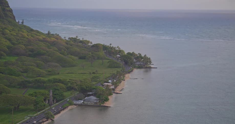 A slow zoom on a scenic coastal highway nestled between a lush green mountain and the tranquil ocean