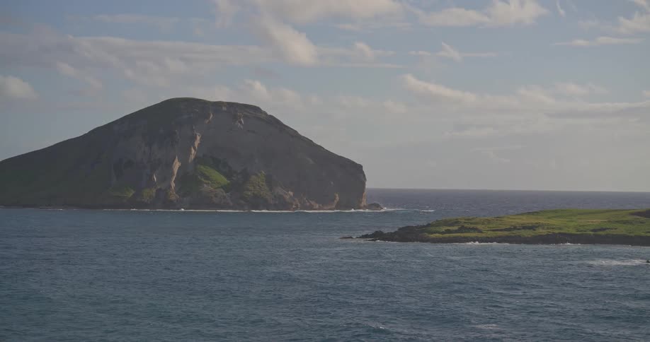 A slow zoom out reveals a large green island known as Mānana Island surrounded by the vast blue ocean off the coast of Oahu, Hawaii