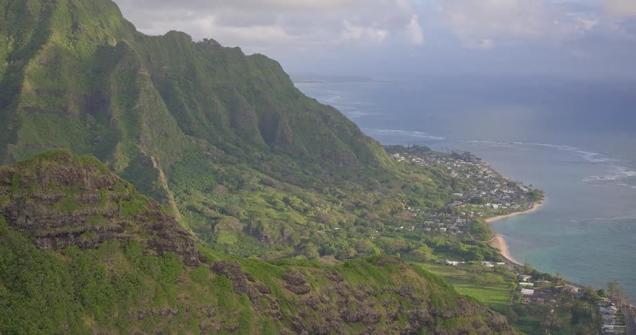 A majestic aerial view pulls back from the lush, green Koolau mountain range to reveal the stunning coastline of Oahu, Hawaii