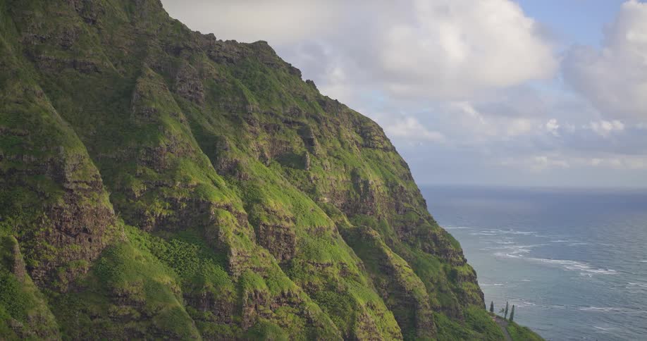 Epic aerial view of the lush, green mountains of Kualoa Ranch overlooking the Pacific Ocean in Hawaii