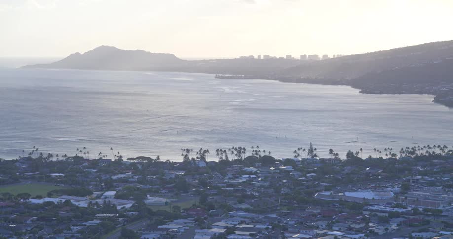 A wide scenic shot of the Honolulu coastline and Diamond Head crater under a bright, hazy sky