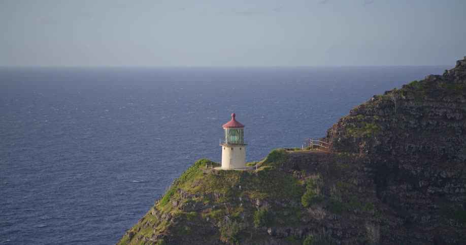 Slow zoom on the picturesque Makapu'u Point Lighthouse perched on a dramatic cliff above the expansive Pacific Ocean on Oahu, Hawaii