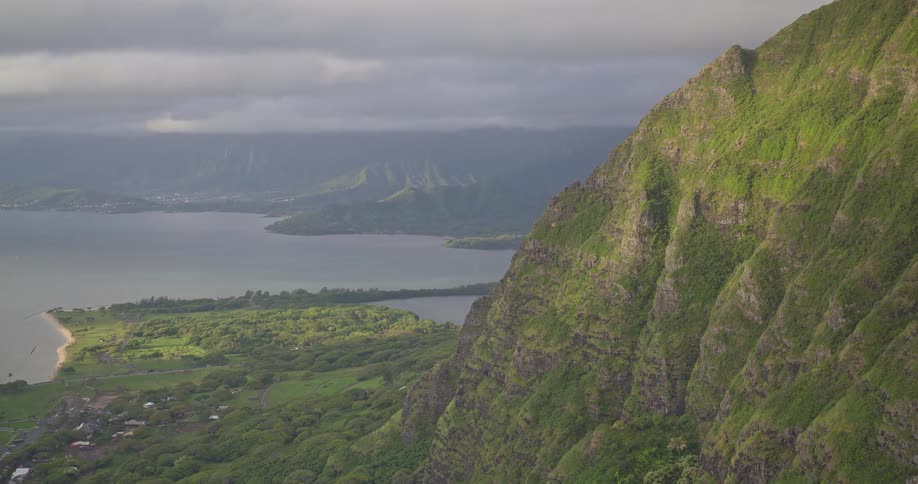 A stunning high-angle shot reveals the lush green mountains and beautiful coastline of Oahu, Hawaii