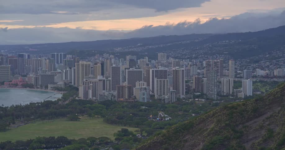 A scenic, wide shot of the Honolulu, Hawaii skyline and Waikiki Beach at dusk from a high vantage point