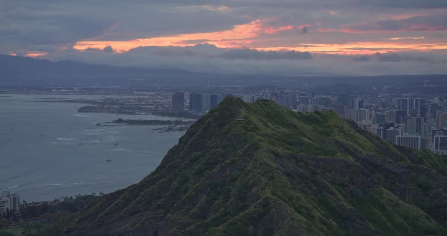 A slow zoom out from the peak of Diamond Head reveals the Honolulu skyline and coastline during a beautiful sunset