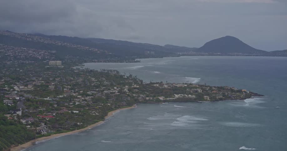 A slow zoom-out aerial view of the southeastern coast of Oahu, Hawaii, on a cloudy and overcast day