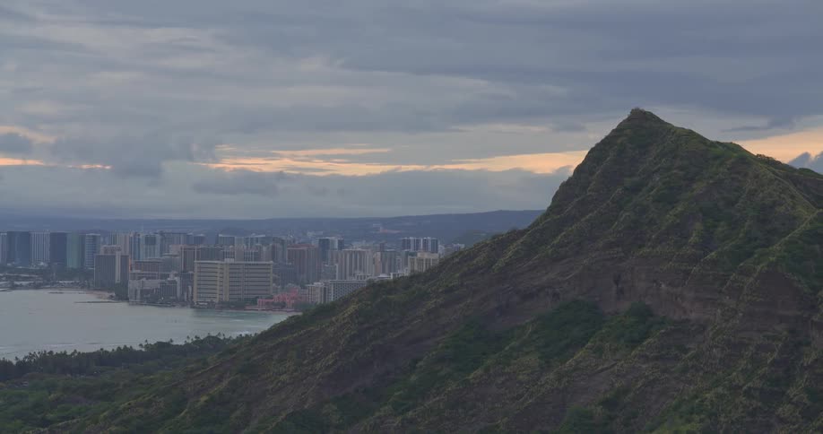 Aerial view reveals Diamond Head crater overlooking the city of Waikiki on the island of Oahu, Hawaii, during a cloudy sunset
