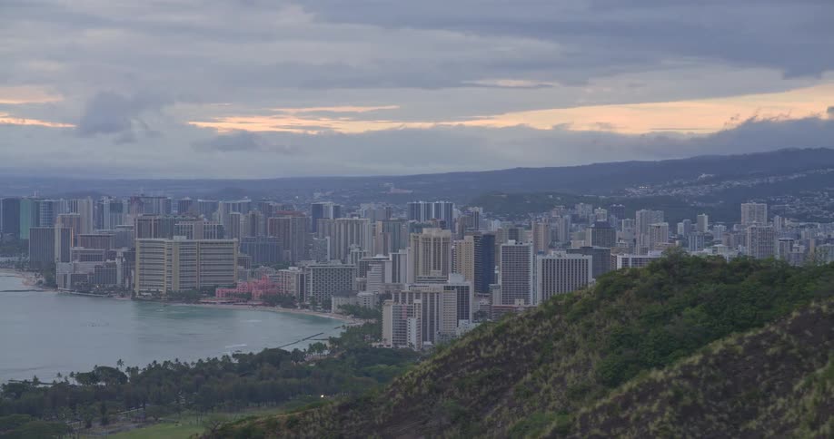 A breathtaking reveal of the Honolulu city skyline and Waikiki Beach from a high vantage point at sunrise