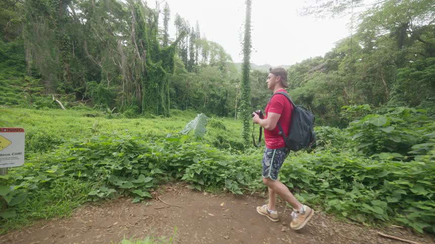 Adventurous photographer on a jungle trail stops to capture the lush scenery in slow motion