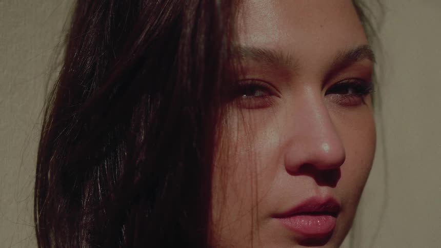 A dramatic close-up of a beautiful woman's face with half in shadow and half in bright sunlight