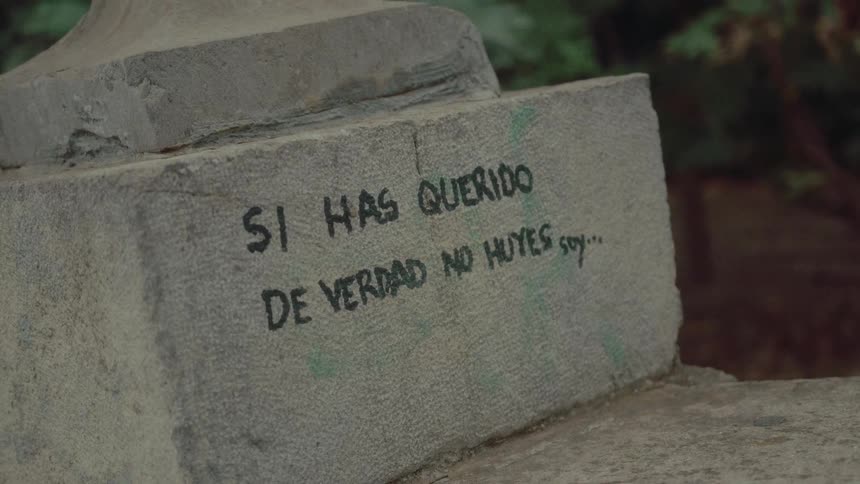 A close-up of a Spanish love message graffitied onto the base of a stone monument
