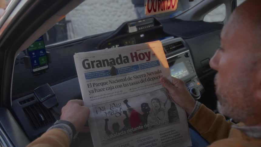 A taxi driver in Spain catches up on the news by reading the 'Granada Hoy' newspaper inside his cab