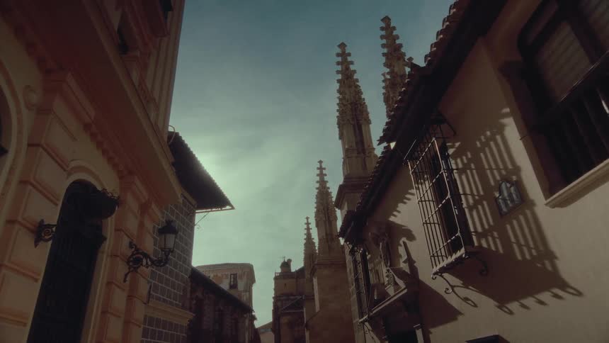 Low angle shot looking up at the spires of the Granada Cathedral from a narrow historic street in Spain