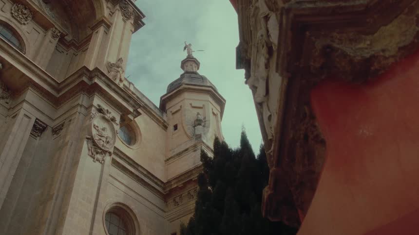 Low angle timelapse of a clock on the tower of a historic European cathedral under an overcast sky