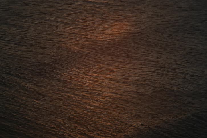 A tranquil high-angle view of the ocean surface as it reflects the warm colors of sunset