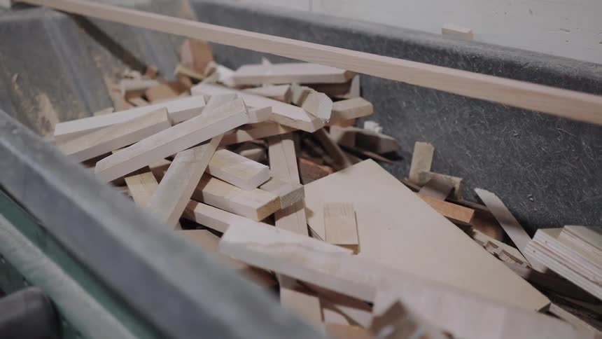 A close-up view shows a large container filled with various scrap wood pieces and offcuts from a woodworking process