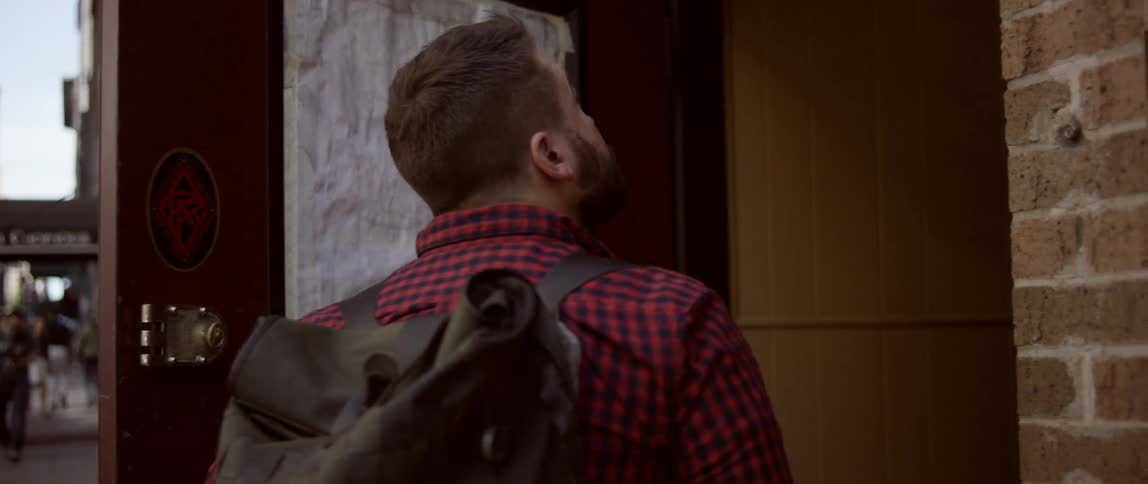 A man walking down a street and entering a tattoo parlor
