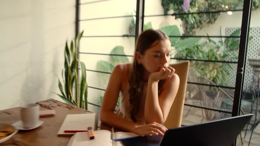 Shaky POV of a woman feeling overwhelmed as she opens her laptop to work in her sunlit home office