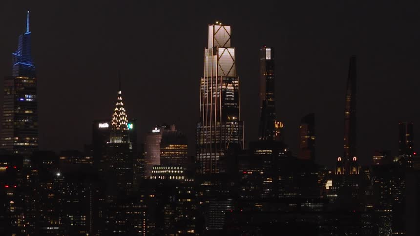 A slow zoom out reveals the dazzling New York City skyline and iconic skyscrapers illuminated against the dark night sky