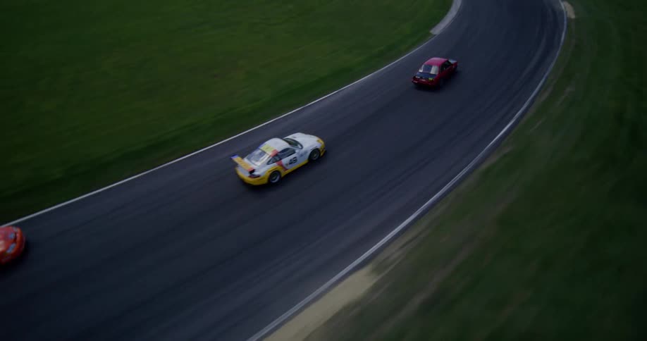 An exciting aerial view follows multiple race cars as they speed around a winding track during a competitive event