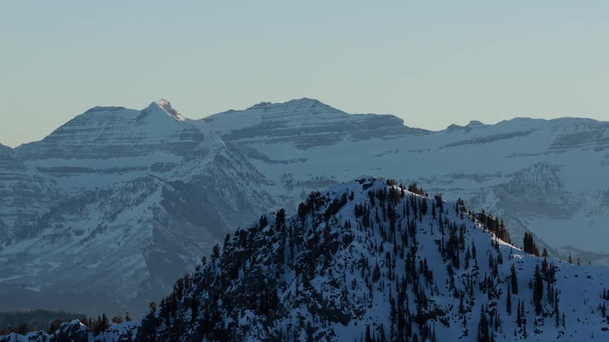 A slow zoom reveals a majestic, snow-covered mountain range during a serene sunrise