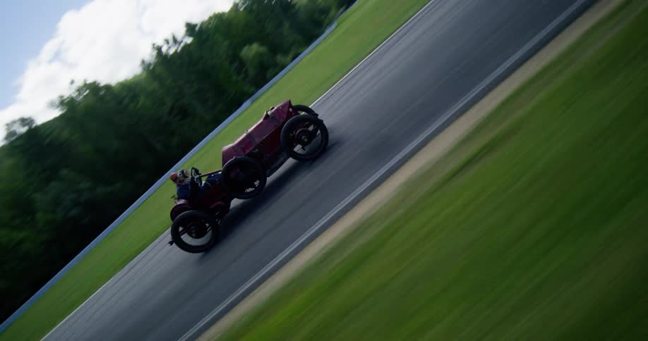 Aerial and tracking shots follow vintage race cars speeding around a scenic racetrack during a competition