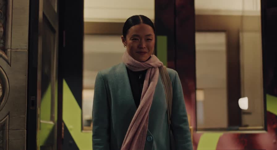Portrait of a content Asian woman smiling warmly while standing in a city doorway in the evening