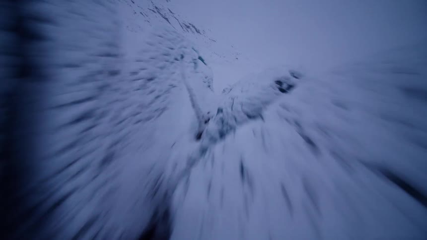 A thrilling first-person view drone flight dives low through a massive, snow-covered ice crevasse on a glacier