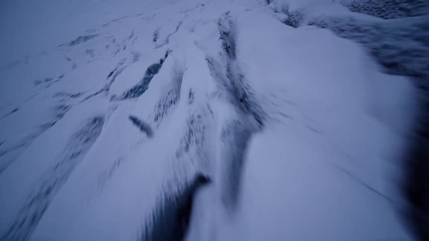 A fast-paced aerial flyover of a vast and desolate snow-covered glacier on a cold winter day