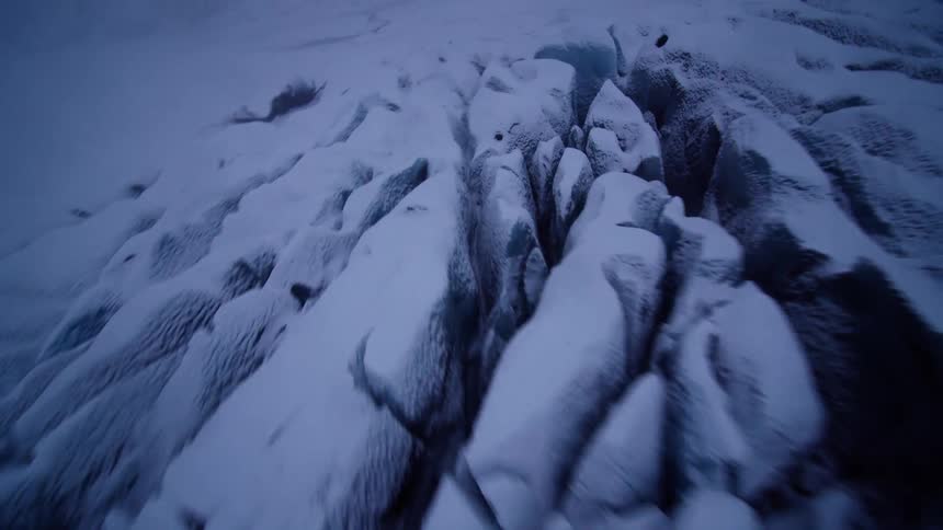 Flying low over a dramatic, snow-covered glacier reveals deep crevasses and a vast, icy wilderness