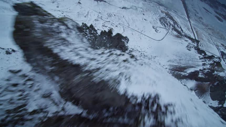 Thrilling first-person view of a drone flying rapidly along a snowy mountain cliffside