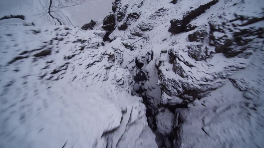 An exhilarating first-person view drone flight soars up a snowy mountain canyon to reveal a vast winter landscape and coastline