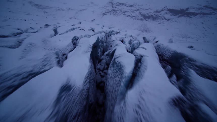 A dynamic first-person view speeds across the rugged, snow-covered terrain of a vast glacier at twilight