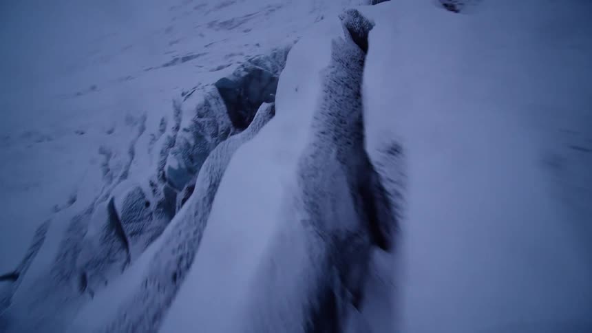 A thrilling, fast-paced aerial journey over a majestic snow-covered glacier with deep blue ice crevasses