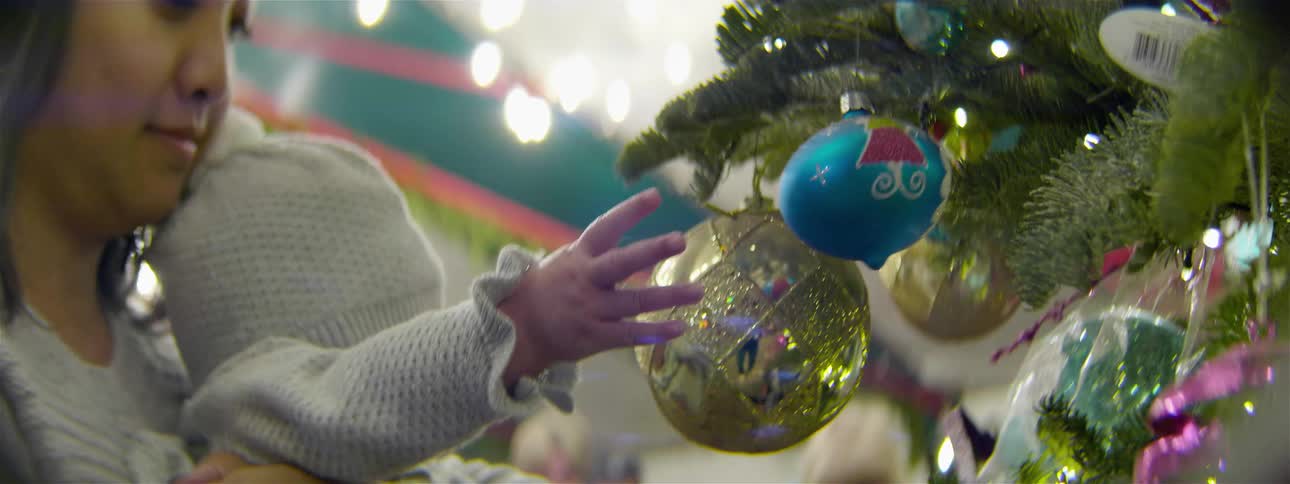 A baby touches ornaments hanging on a christmas tree
